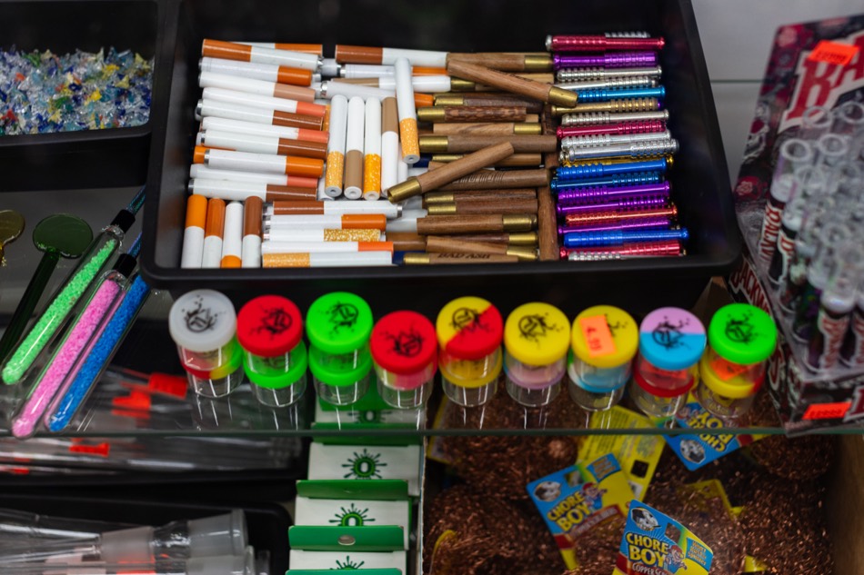 Pipes, one-hitters, and small accessory jars on counter